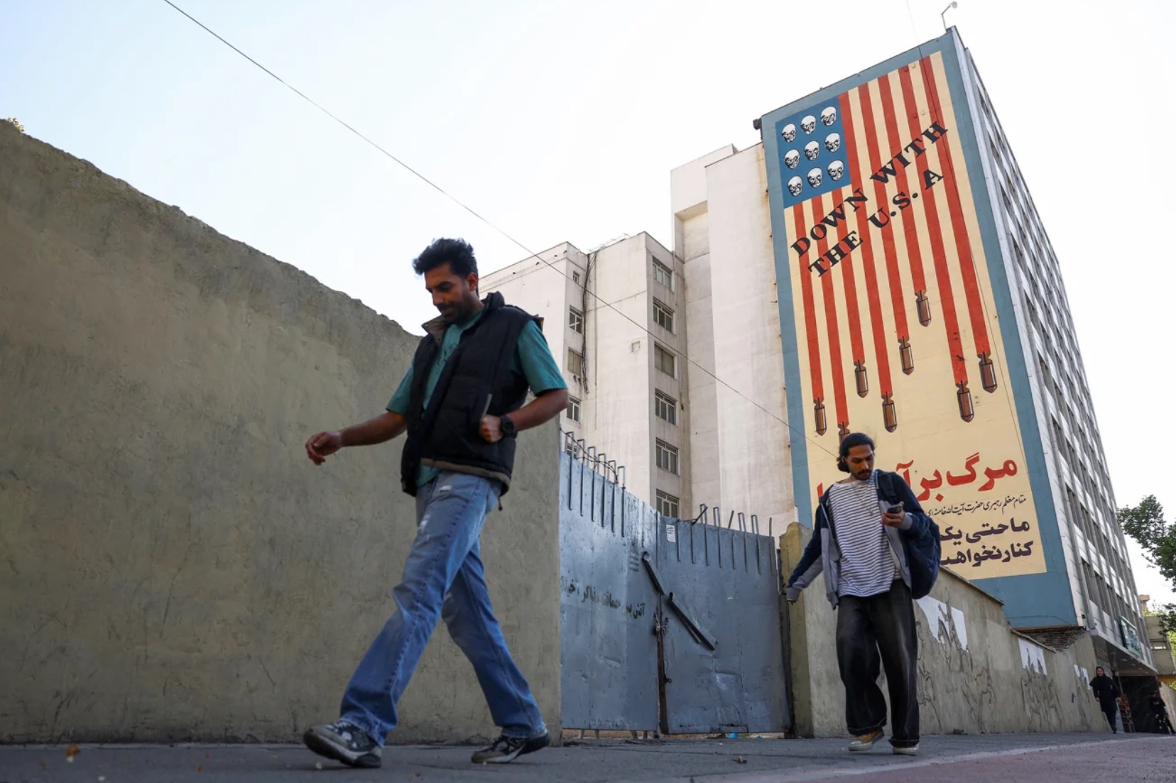 周四，人们走过德黑兰一栋建筑物上的反美壁画